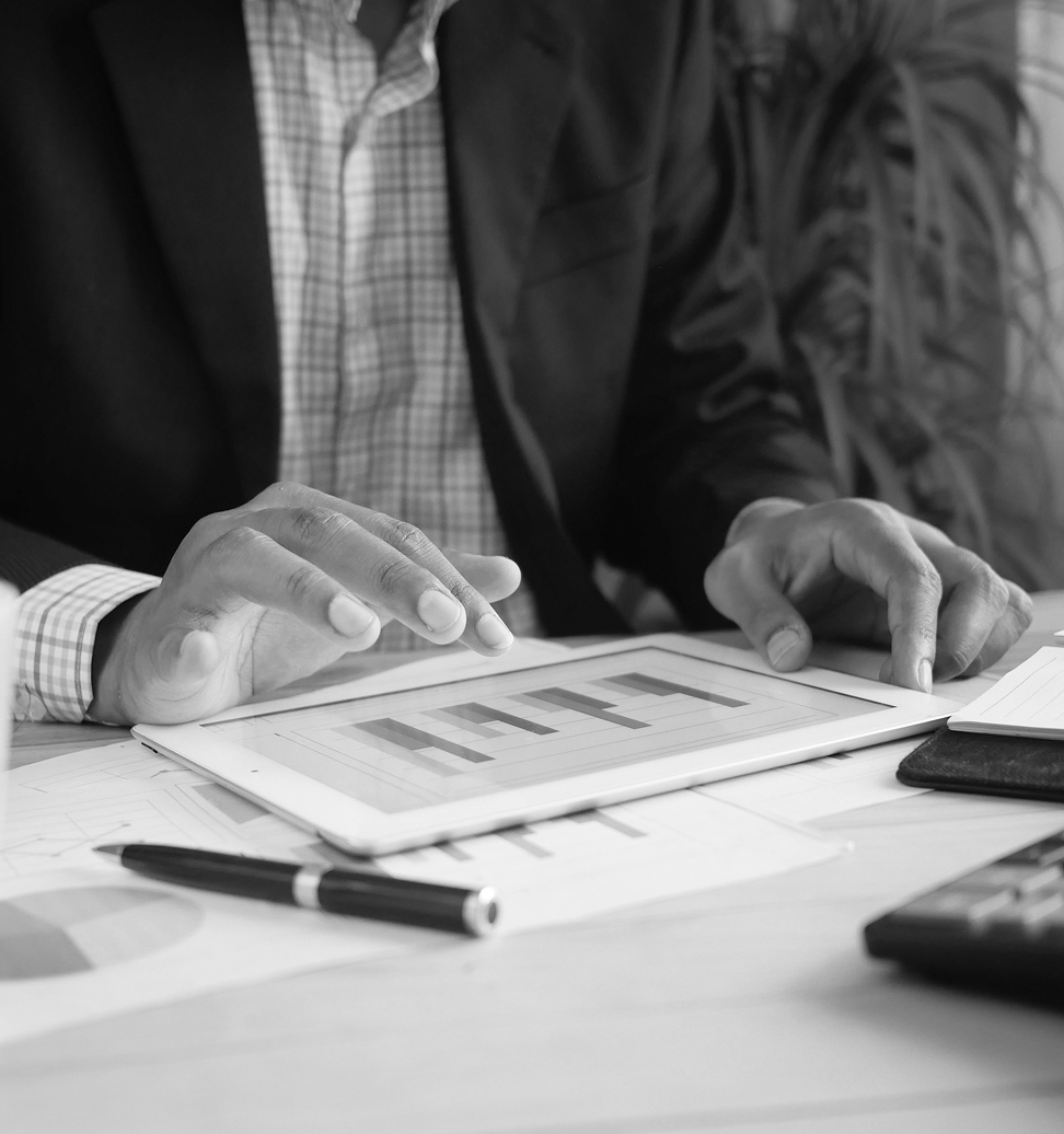 a black and white photo of a man holding his finger over a tablet with a bar chart on the screen